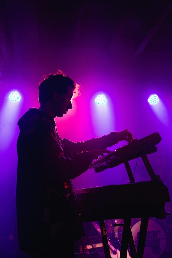 A DJ mixing music on stage with vibrant purple lighting creating a moody atmosphere.